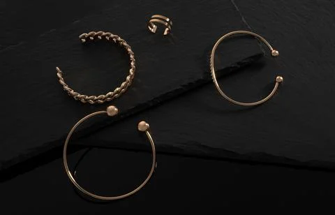 Three modern bracelets and double shape ring on black stone trays with copy s Stock Photos