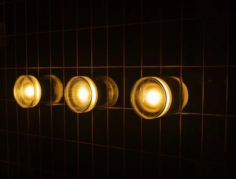 Three modern round warm light lamps, circle shape, mounted on striped grid .. 写真素材