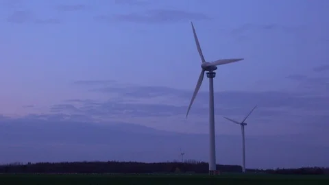 Three modern wind turbines generating sustainable energy in a field at evening Stock Footage 82731771