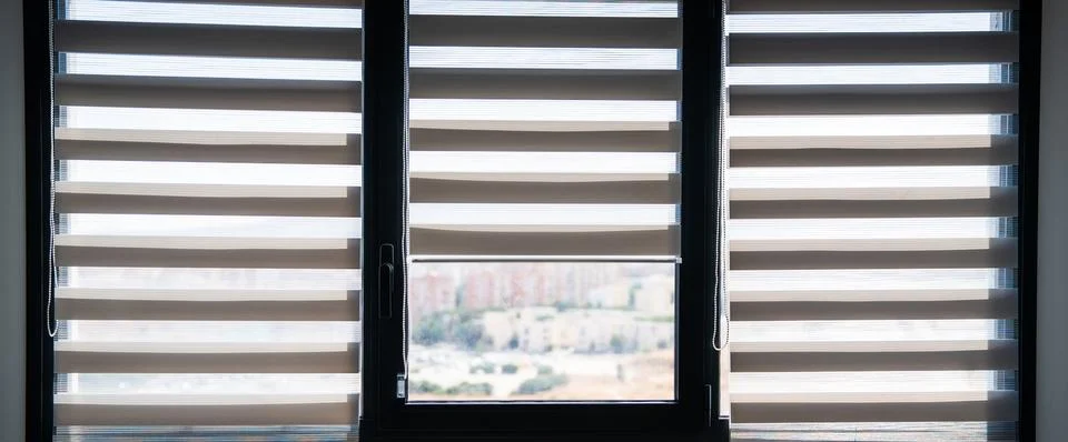Three modern windows with zebra roller blinds filtering daylight Stock Photos