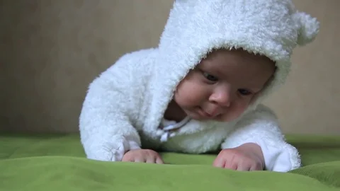 Three month old baby lying on the bad and wants to crawl 스톡 동영상 72072492