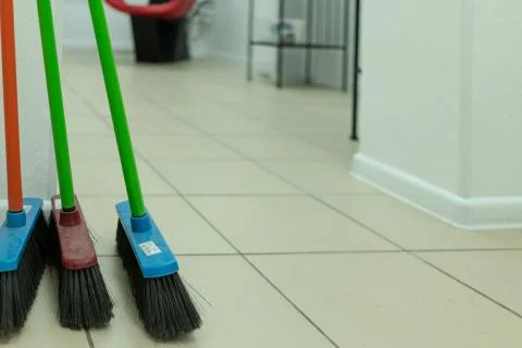 Three mops of different colors stand near the wall Foto stock