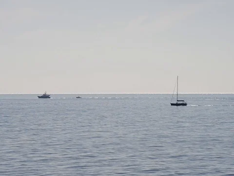 Three motor boats of various sizes sail the horizon on a summer day Stock Footage 83536744
