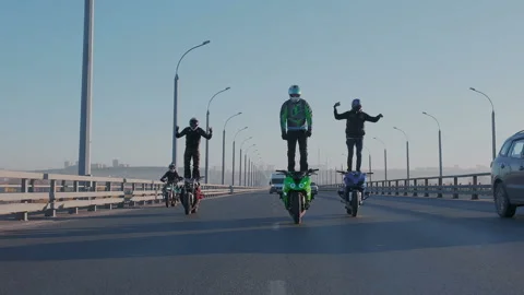 Three motorcyclists synchronously perform spectacular acrobatic show on a moving Stock Footage 105011753
