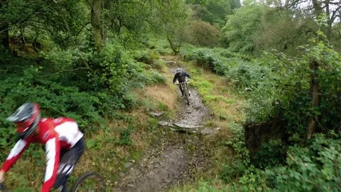 Three mountain bikers cycling down muddy wet trail together, drone aerial 4K Stock Footage 101107266