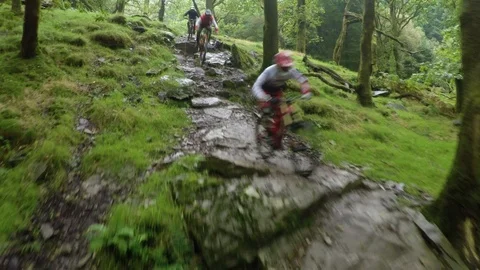 Three mountain bikers going down wet rock table close tight, drone aerial 4K Stock Footage 101106930