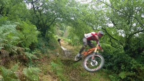 Three mountain bikers going over small rock jump, drone aerial 4K Stock Footage 101106960