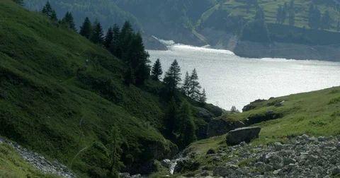 Three mountain bikers head away from camera in mountains overlooking a lake. Vídeos de archivo 78031377