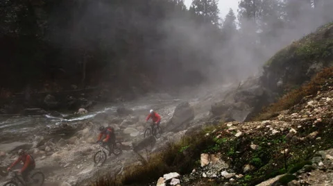 Three Mountain Bikers Riding Through Steam In The Mountains Slow Motion Stock Footage 64310044