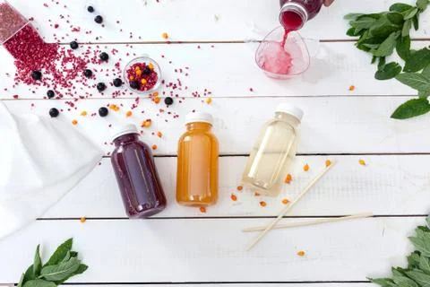 Three multi-colored bottles with fruit drink on a white board. View from abov Stock Photos