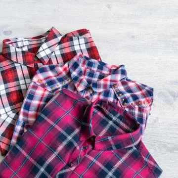 Three multi-colored checkered women's shirts lying neatly folded Stock Photos