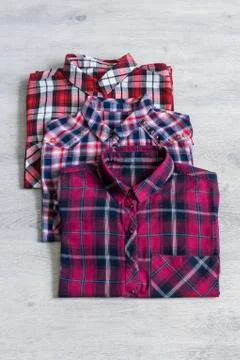 Three multi-colored checkered women's shirts lying neatly folded Stock Photos