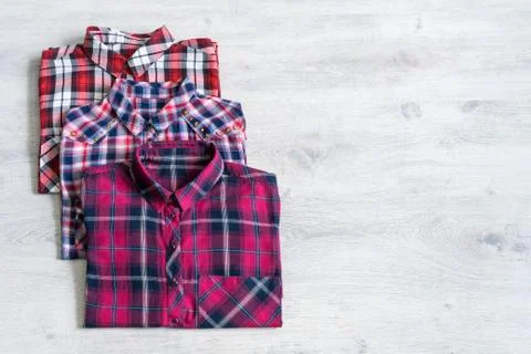 Three multi-colored checkered women's shirts lying neatly folded Stock Photos