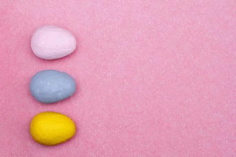 Three multi-colored decorative eggs on a pink background. Stock Photos