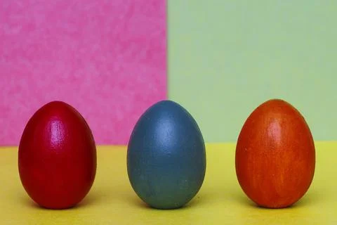 Three multi-colored decorative eggs on a three-colored background. Stock Photos