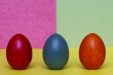 Three multi-colored decorative eggs on a three-colored background. Stock Photos