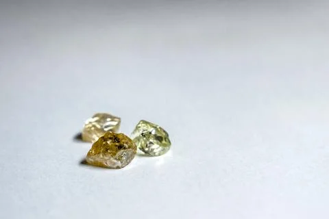 Three multi-colored diamonds lie on a white plastic surface Stock Photos