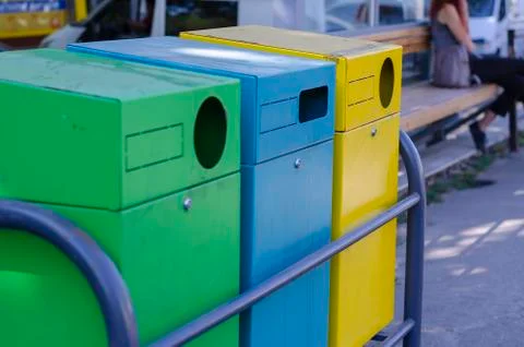 Three multi-colored garbage containers on a city street. Stock Photos