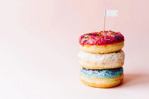 Three multi-colored glazed cream donuts stacked on each other Stock Photos