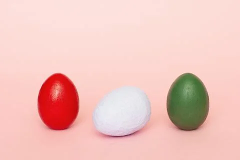 Three multi-colored handmade eggs on a pastel pink background. 스톡 사진