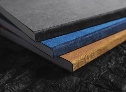 Three multi-colored notepads close-up on dark textured background Stock Photos