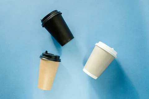 Three multi-colored paper cups for coffee lie on a blue background. Coffee cu Stock Photos