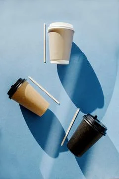Three multi-colored paper cups for coffee and wooden sticks for mixing sugar Stock Photos