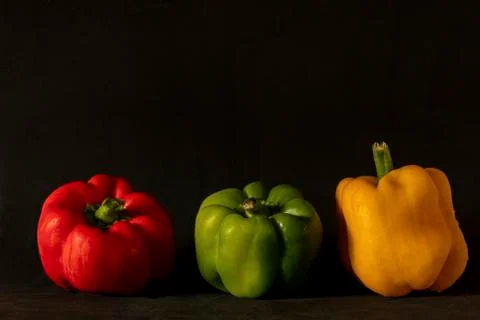 Three multi-colored peppers posing for the photo on a dark background. Stock Photos