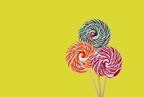 Three multi-colored round lollipops on wooden sticks, copy space Stock Photos