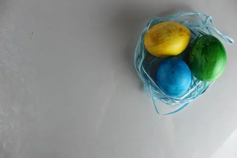 Three multi-coloured yellow green blue eggs for the Easter holiday lie next t Stock Photos