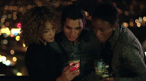 Three multi-ethnic friends look at phone Stock Footage 65025551