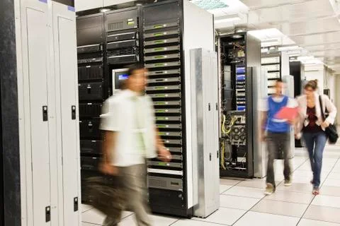 Three multi-ethnic technicians working in a large computer server room. Stock Photos