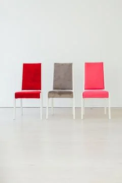Three multicolored chairs in the interior of an empty white room Foto stock