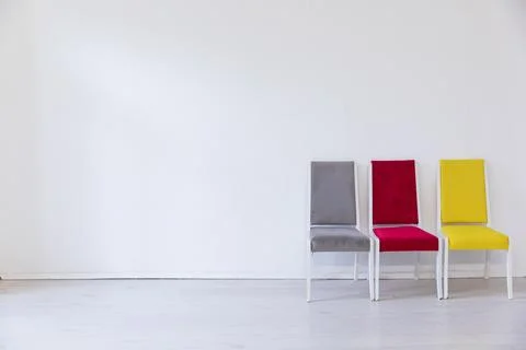 Three multicolored chairs in the interior of an empty white room Stock Photos