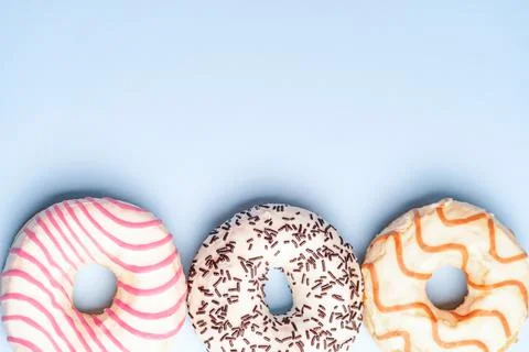 Three multicolored donuts on a blue background, top view 库存照片
