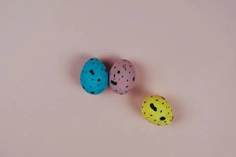 Three multicolored Easter quail eggs isolated on pink background. Happy Easter Stock Photos