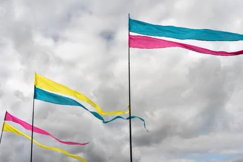 Three multicolored flags against a cloudy sky background Stock Photos