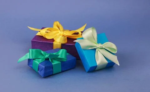 Three multicolored gift boxes on blue background. Stock Photos