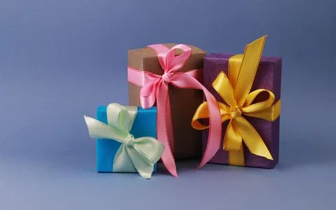 Three multicolored gift boxes on blue background. Stock Photos