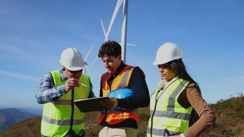 Three multicultural engineers reviewing blueprints in digital tablet at win.. Stock Footage 294975828