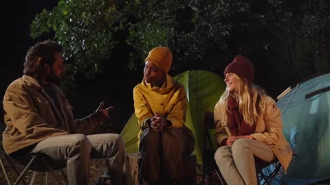 Three multicultural friends enjoying talking and laughing at winter night Stock Footage 261765907
