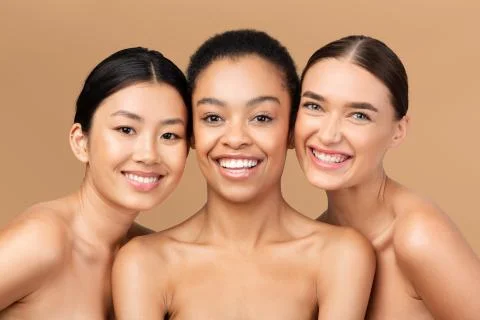 Three Multicultural Ladies Models Posing Smiling On Beige Studio Background Stock-Fotos