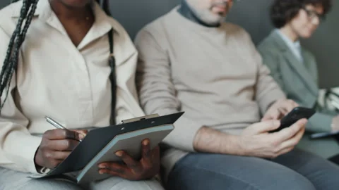 Three Multiethnic Applicants Filling Forms, Using Phone, Waiting For Interview Stock Footage 236700478