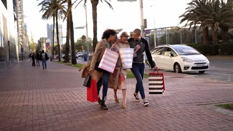 Three multiethnic girlfriends having fun, shopping and laughing while walking on Stock Footage 240939406