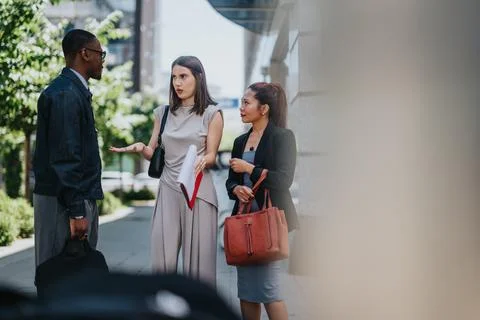 Three multiracial colleagues having a conversation outdoors on a bright day Stock Photos