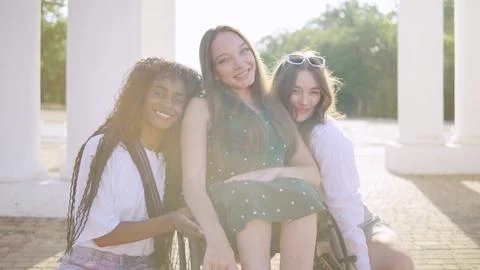 Three multiracial friends one disabled in a wheelchair enjoying a sunny day.. Stock Photos