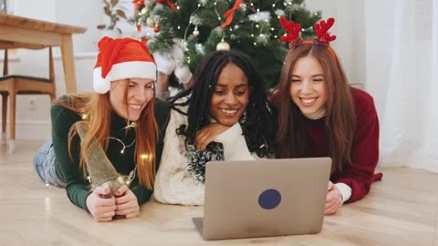 Three multiracial friends relax on the floor, wearing festive attire, as they Stock Footage 319453379