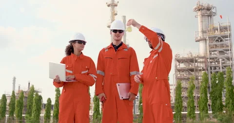 Three multiracial refinery workers review liquid sample near laptop, conducting Stock Footage 344402687