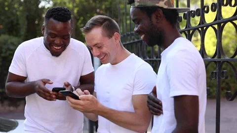 Three multiracial students communicate with each other, look at the phone and Stock Footage 140842383