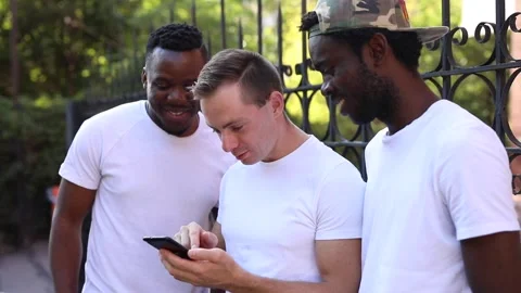 Three multiracial students communicate with each other, look at the phone and Stock Footage 140842481